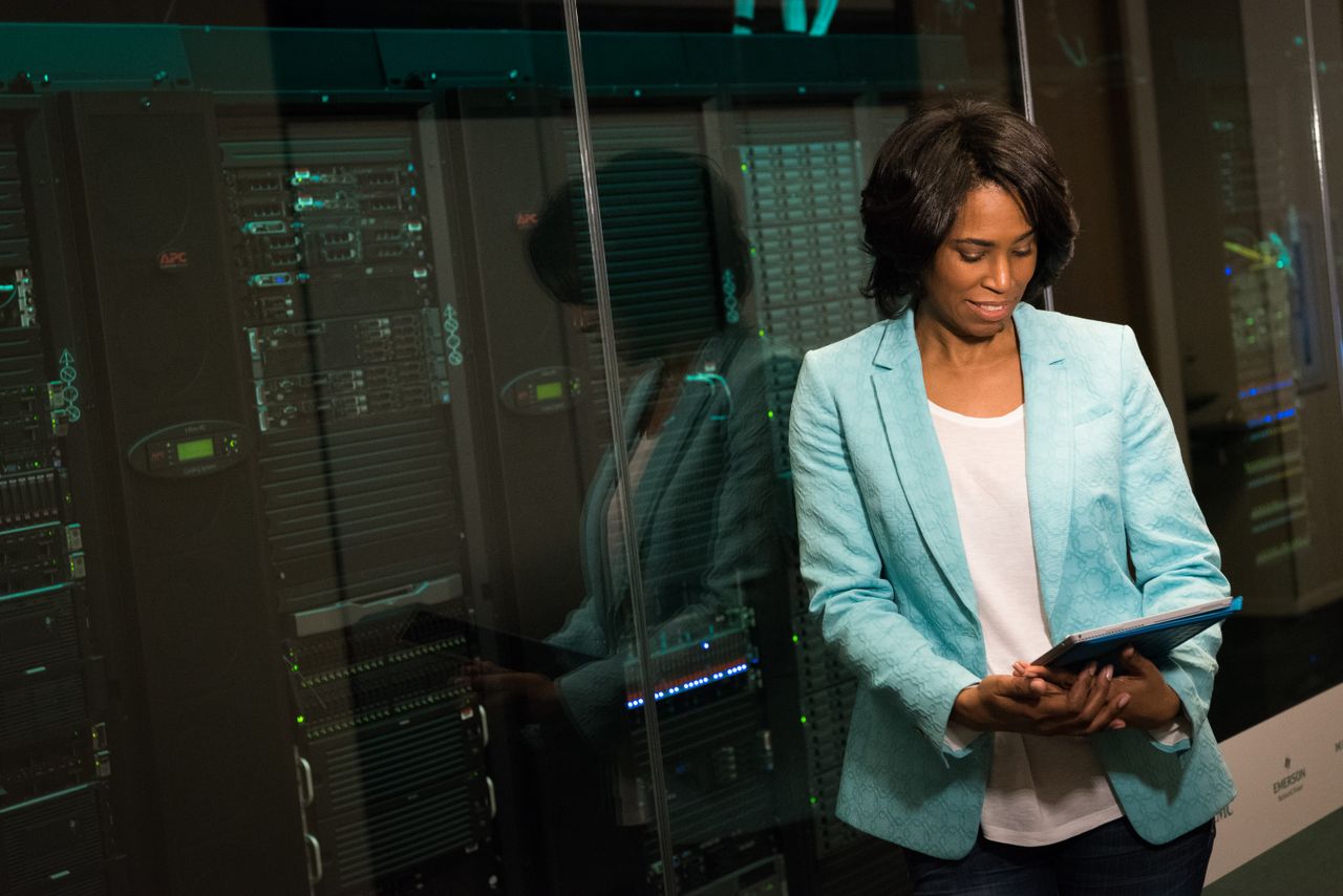 our-mission Female IT professional examining data servers in a modern data center setting.