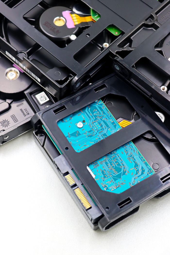 why-choose-us Close-up of multiple black internal hard drives stacked on a white surface showcasing circuit boards.